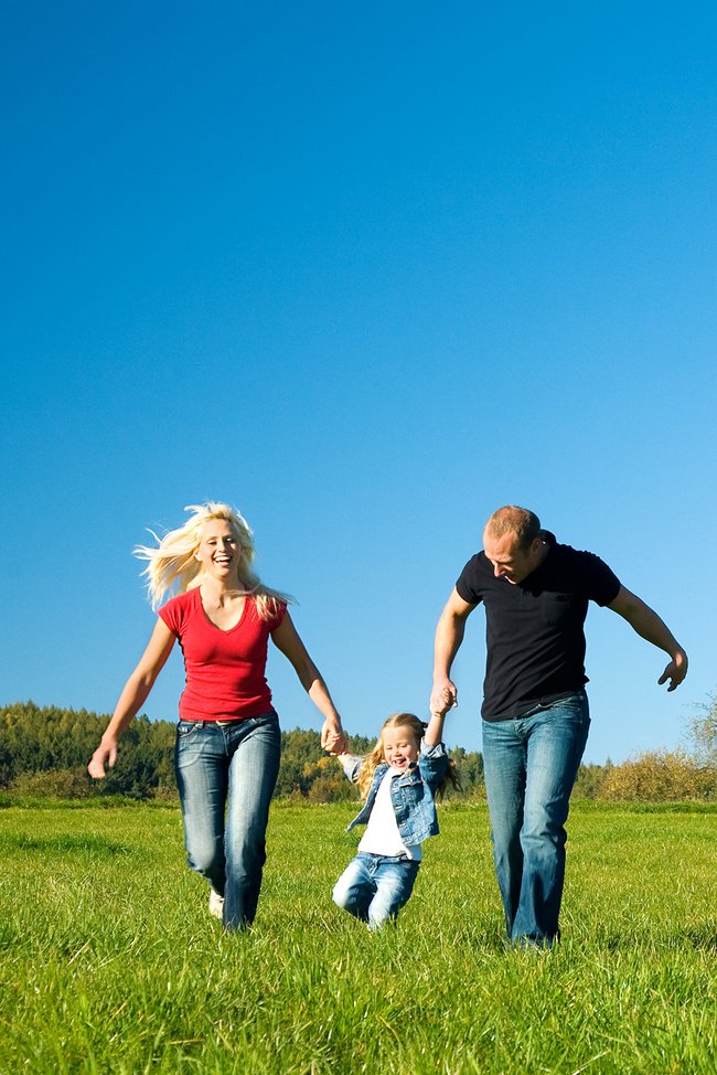 Familie spielt auf der Wiese mit der Tochter.