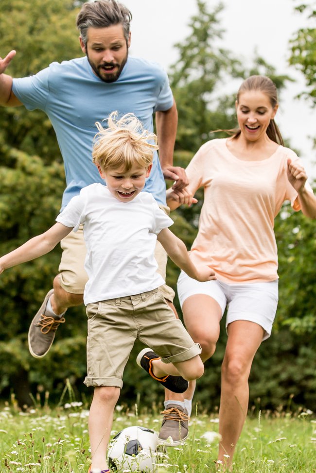 Familie spielt Fußball im Garten.